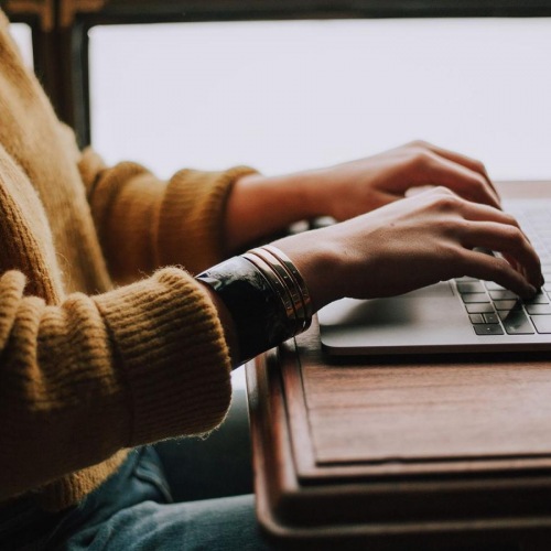 Your new home is waiting woman types on her laptop near large window