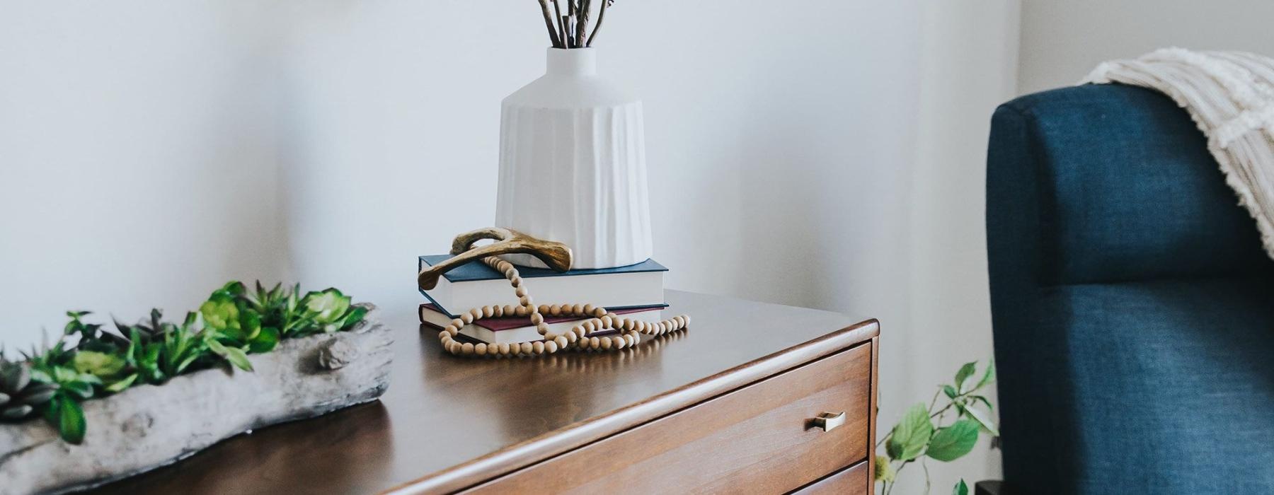 a dresser with a vase of plants on top