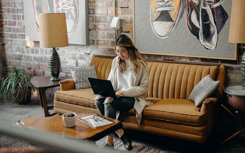 a woman sitting on a couch working on a laptop